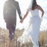 Newlywed couple holding hands in grass